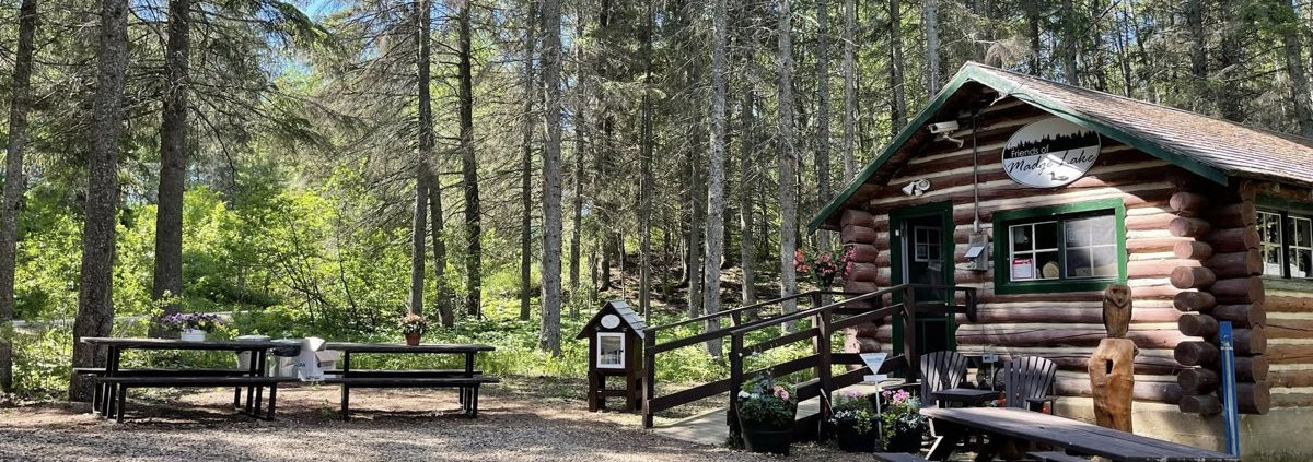 Log cabin-style Treats and Treasures store at Madge Lake, surrounded by trees and picnic tables.
