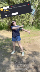 Ella dramatically spraying bug spray in a forest clearing while wearing sunglasses and casual hiking clothes.