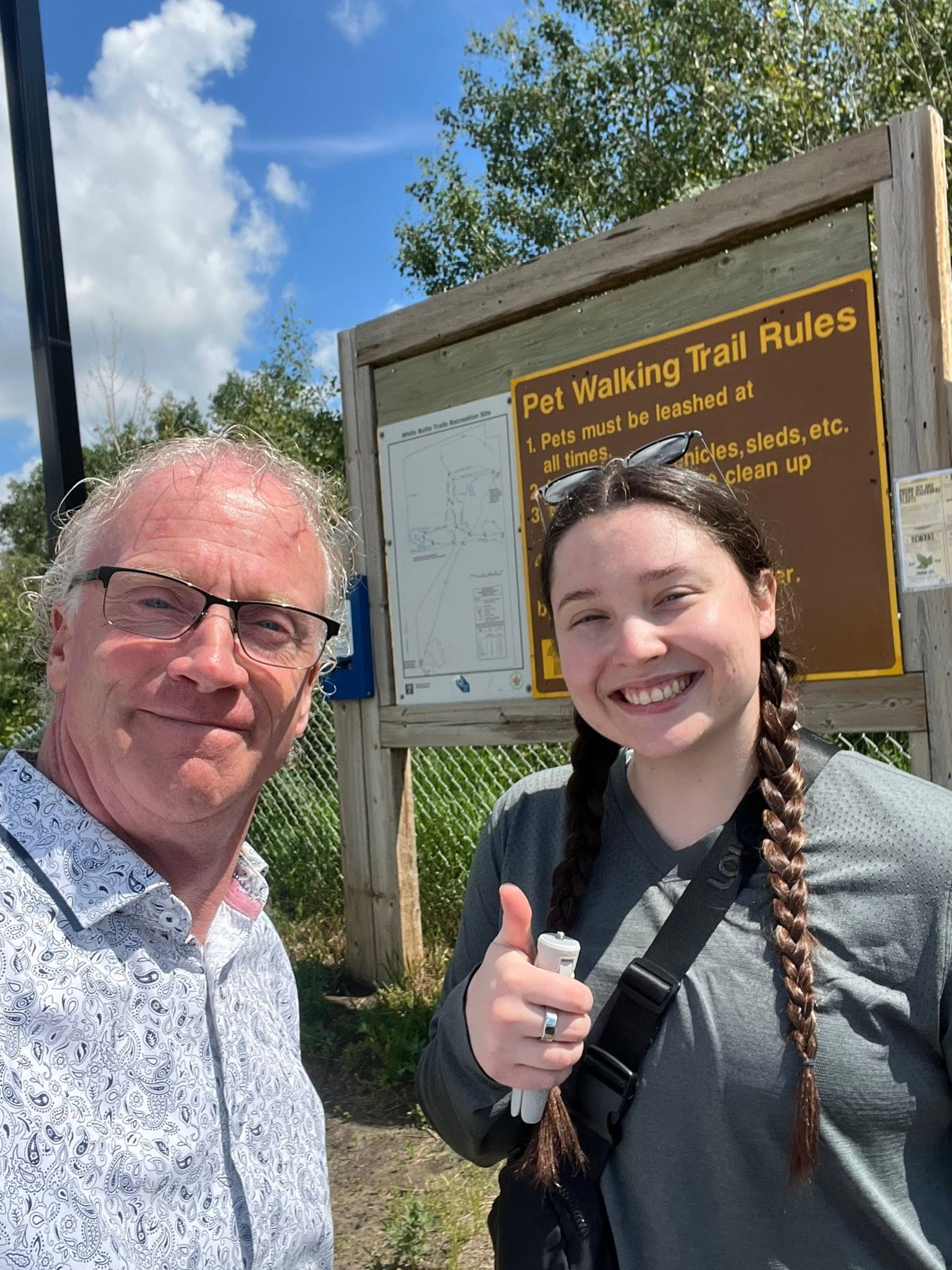 Brad Crassweller and Saskatchewan Trails Storyteller Ella Gidluck smiling at the White Butte Trails trailhead.