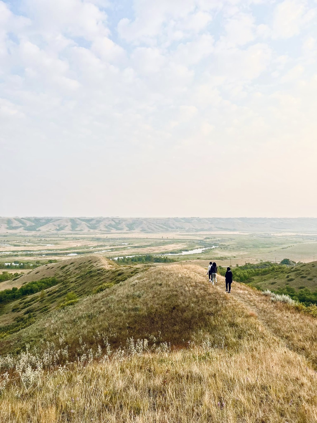 Hikers walking along a prairie ridge overlooking Hidden Valley Wildlife Refuge in Saskatchewan.