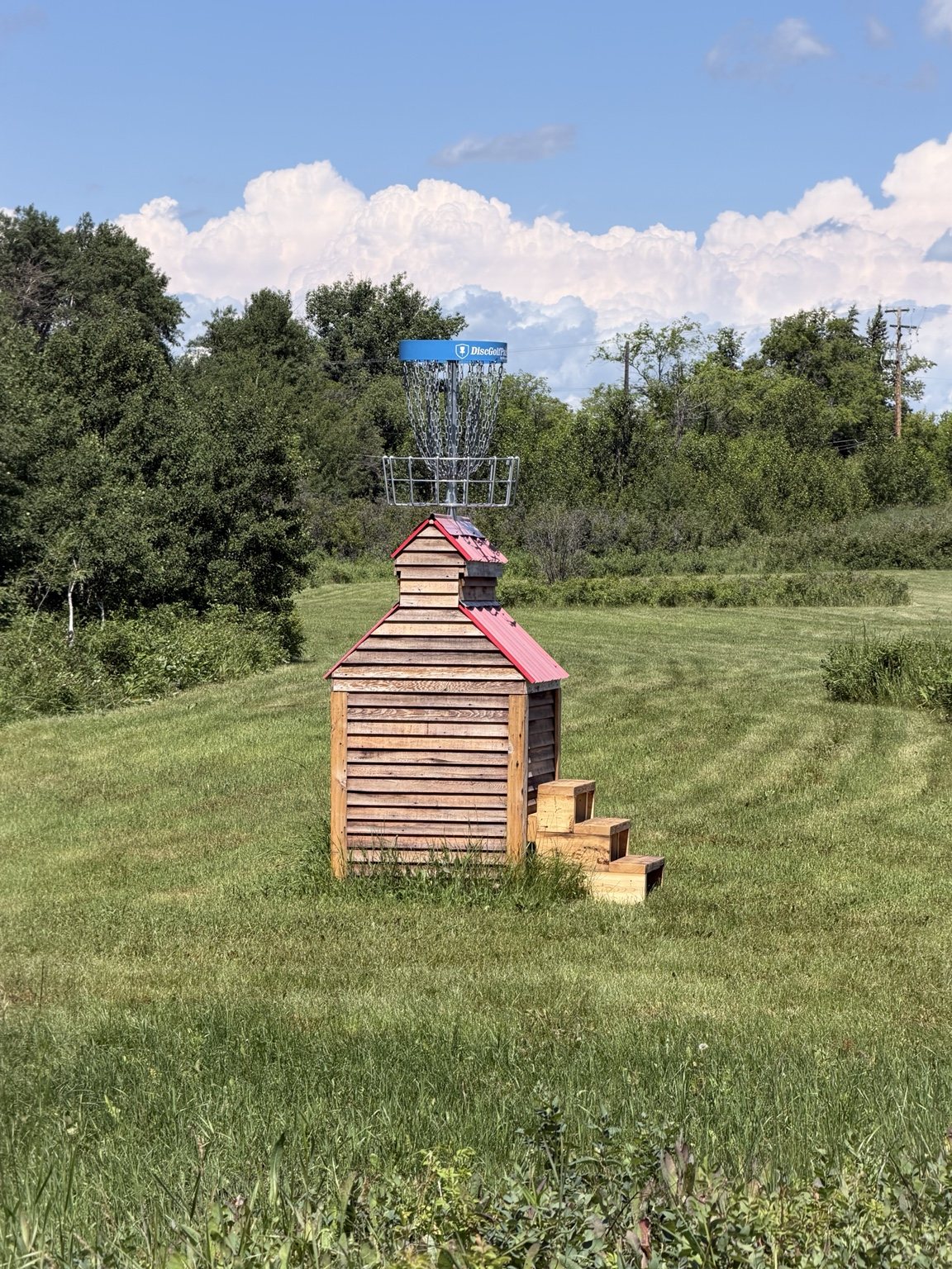 Disc golf basket mounted on a small grain-elevator-style structure