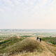 Hikers walking along a prairie ridge overlooking the South Saskatchewan River Valley at sunset.
